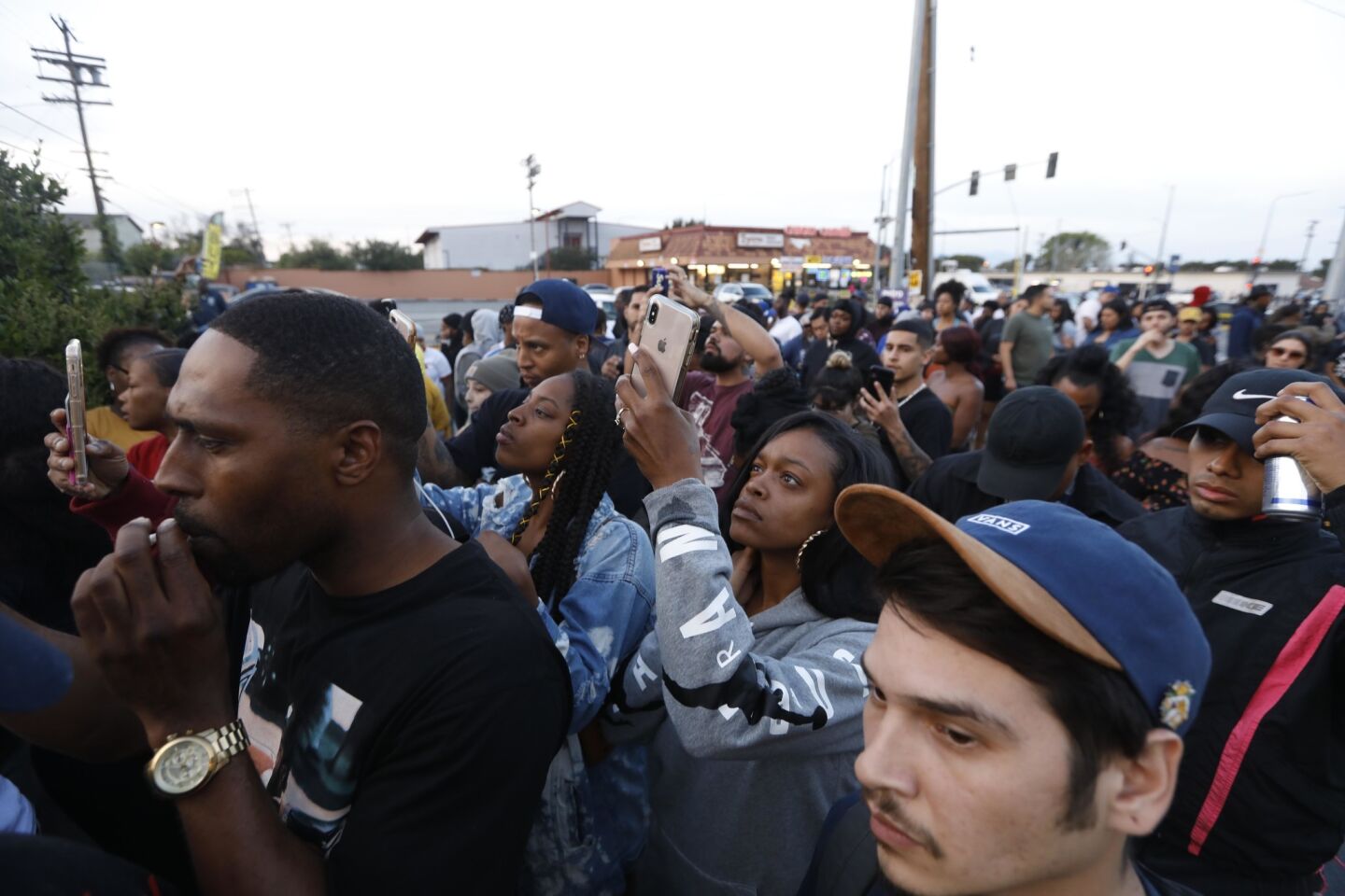 A crowd of people gathers at the scene where rapper Nipsey Hussle was killed Sunday.