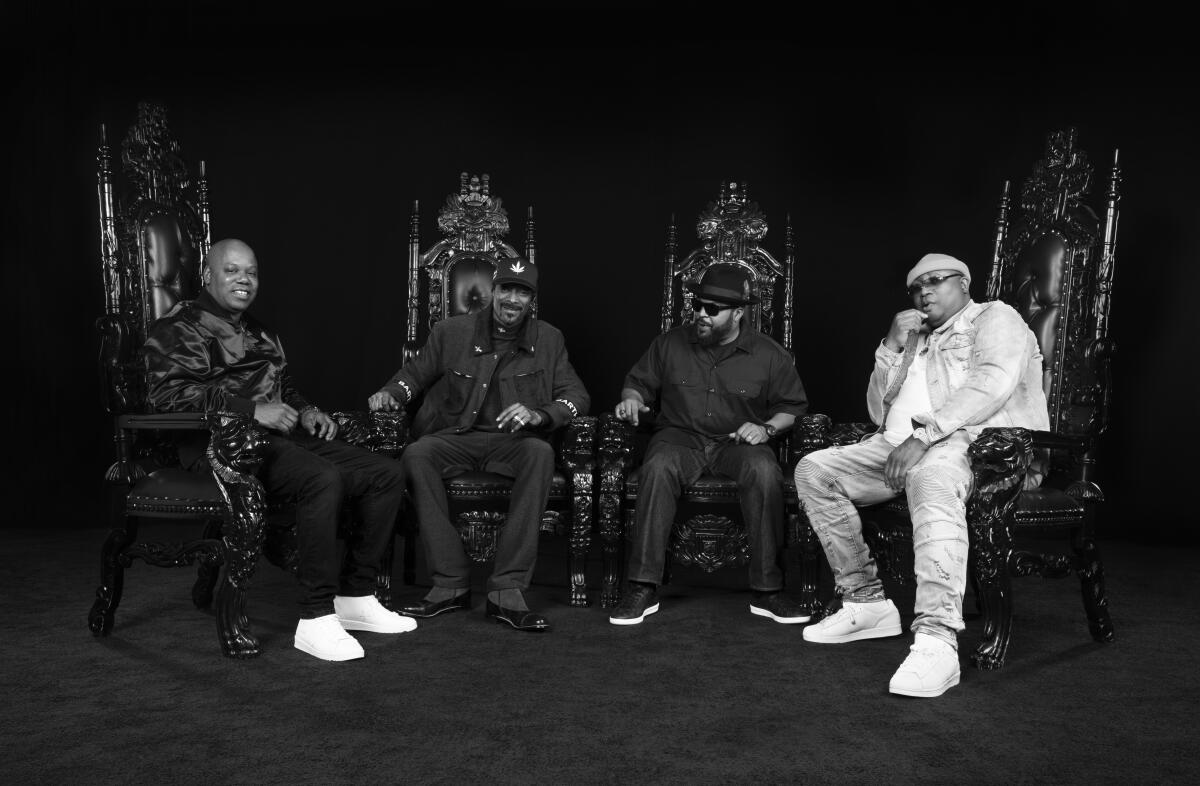 Four middle-aged rappers sit on mock thrones