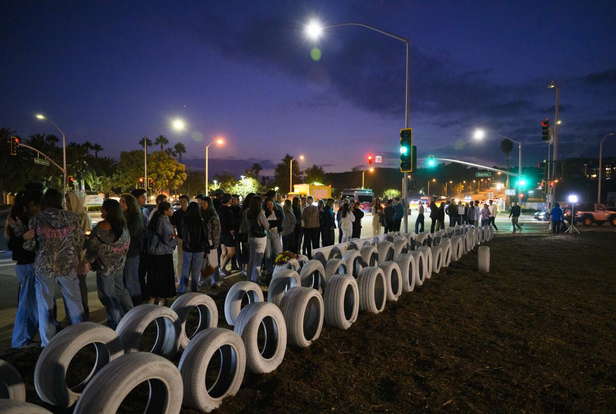 La gente se encuentra junto a docenas de neumáticos blancos en un monumento conmemorativo al lado de la carretera.