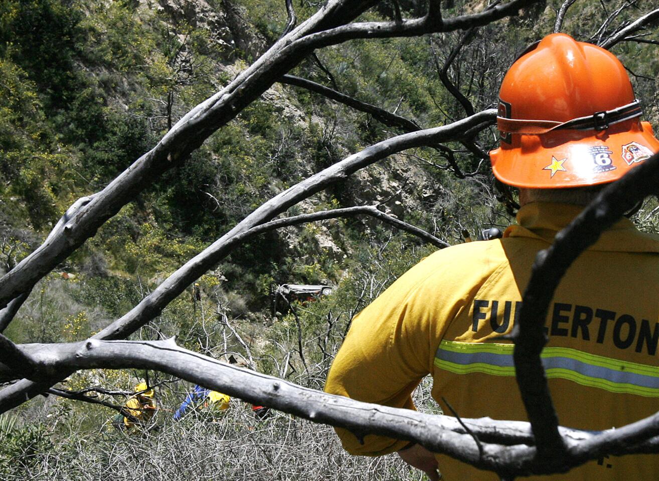 A fireman watches rescue workers climb to the top of a sharp drop where vehicle was found in the Angeles Crest Highway at mile marker 31.82 on Monday, April 8, 2013. No victims were found at the scene.