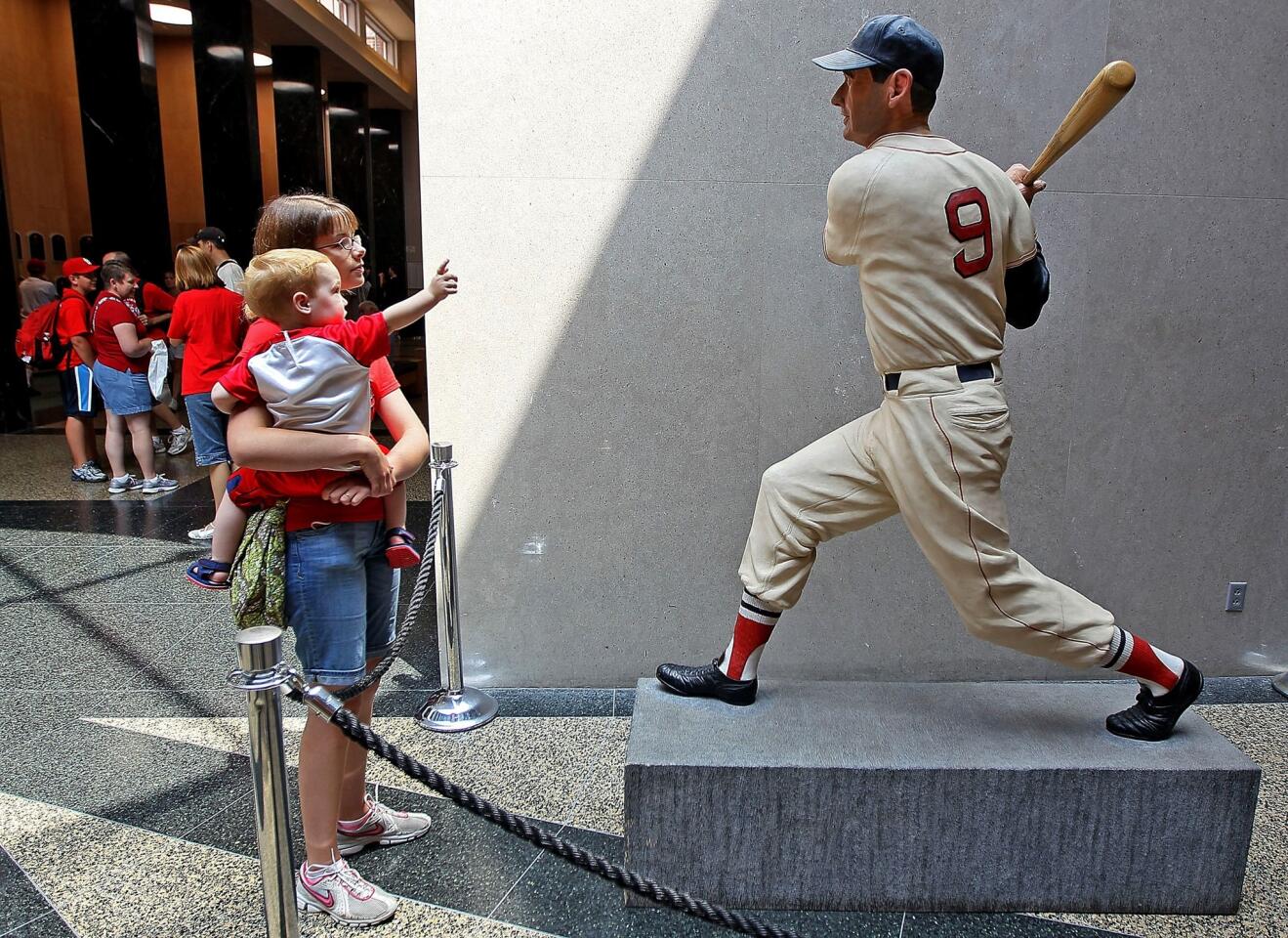 Visitors to the Baseball Hall of Fame and Museum view a statue of Ted Williams during induction weekend in 2010.