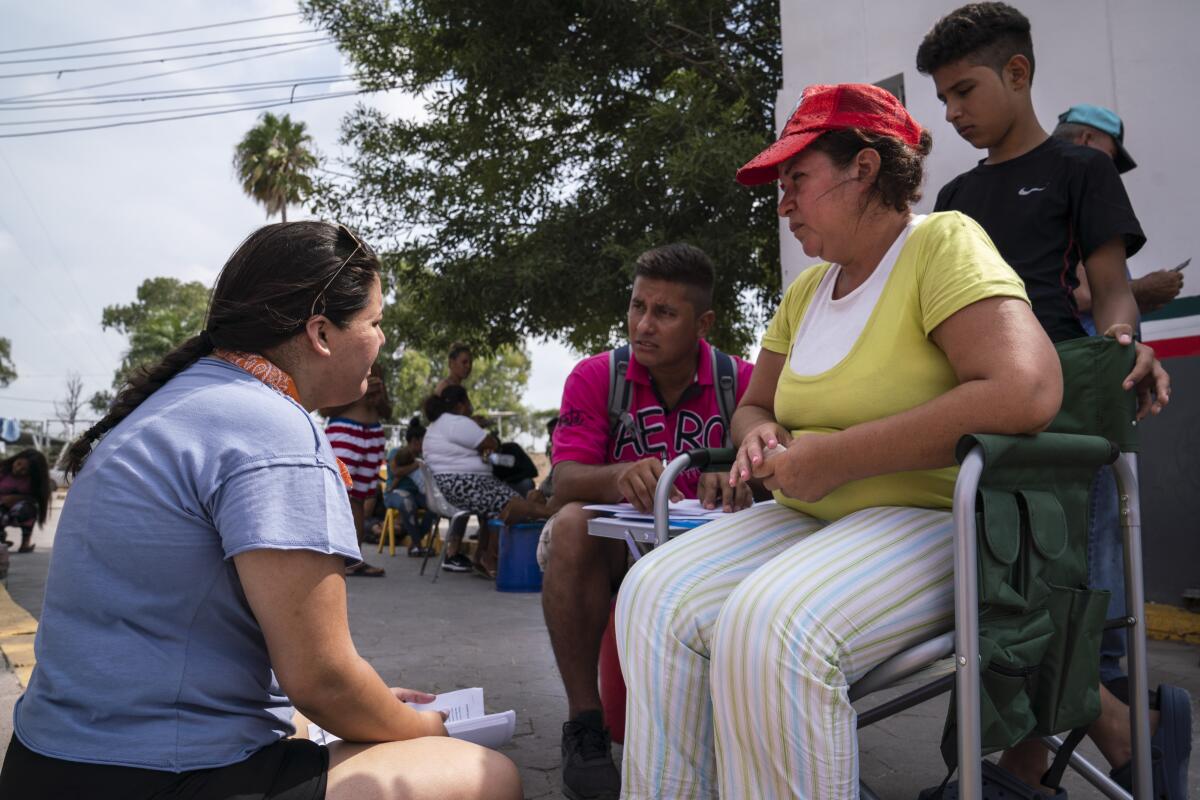 Volunteer lawyer Joan Orejuela, left, listens to asylum seekers William Erazo Antunez, 36, wife Claudia Oliva Garcia, 42, and their son William at a workshop on asylum claims on Aug. 24, 2019. The family was sent to Matamoros to wait for their asylum claim in Mexico under the Trump administration's "Remain in Mexico" policy.