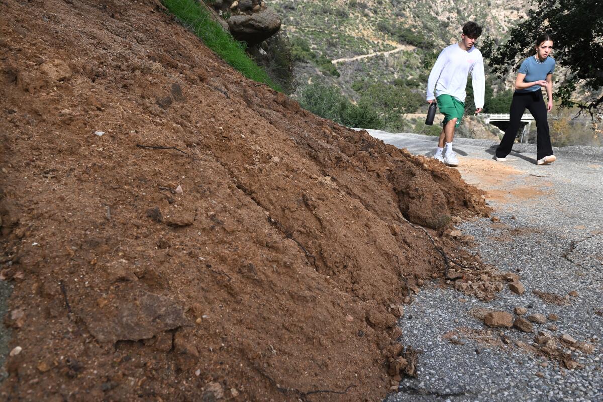 A couple walks by a mudslide in Eaton Canyon as recent storms have caused damage on local hiking trails. 