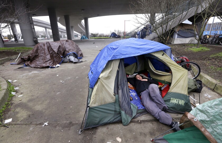 A man lies in a tent near an overpass in Seattle in 2016.