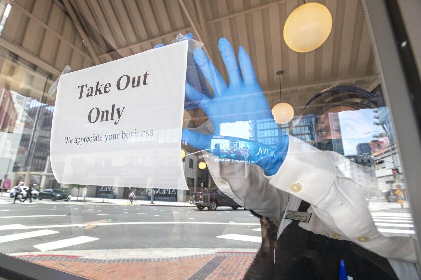 LOS ANGELES, CA - JULY 01, 2020: Mary Granados, a waitress at The Original Pantry in Downtown Los Angeles, tapes a sign to the window letting customers know that they are now only open for take out service. California Gov. Gavin Newsom announced today that for the next 3 weeks, restaurants in Los Angeles County and a number of other counties statewide will only be allowed to have take out and delivery service due to an increase in coronavirus cases. (Mel Melcon / Los Angeles Times)