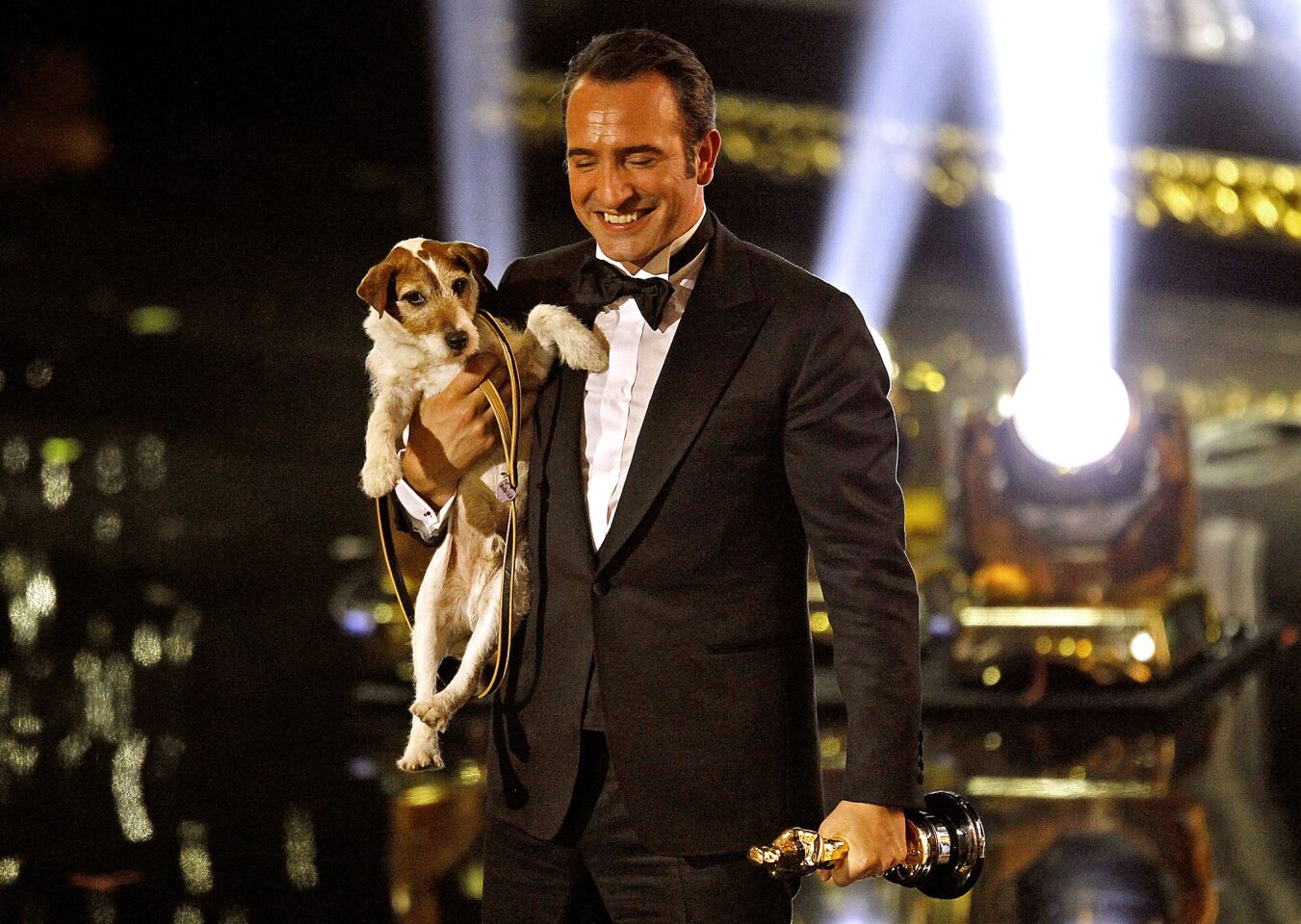 Jean Dujardin, after winning lead actor for "The Artist," walks off the stage with Uggie the dog at the 84th Academy Awards.