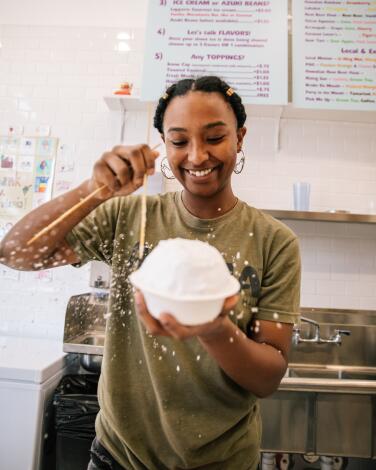 A smiling person holds up a large bowl of shaved ice