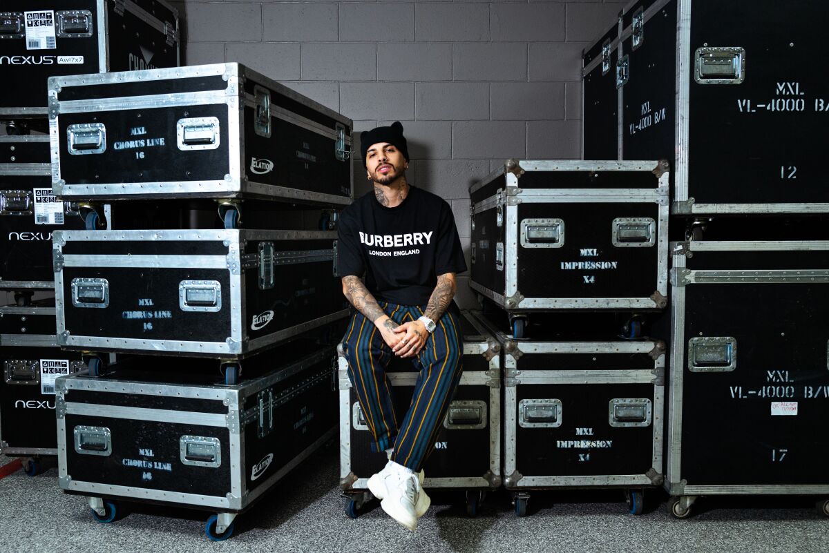 A man wearing a Burberry T-shirt sits on one of many music transport cases