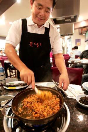 At On Dal 2, owner Kihoa Kim serves fried rice with spicy crab sauce to diners at the table. Kim's wife, Hyo-Sook, is chef at the restaurant, which specializes in spicy crab hot pots.