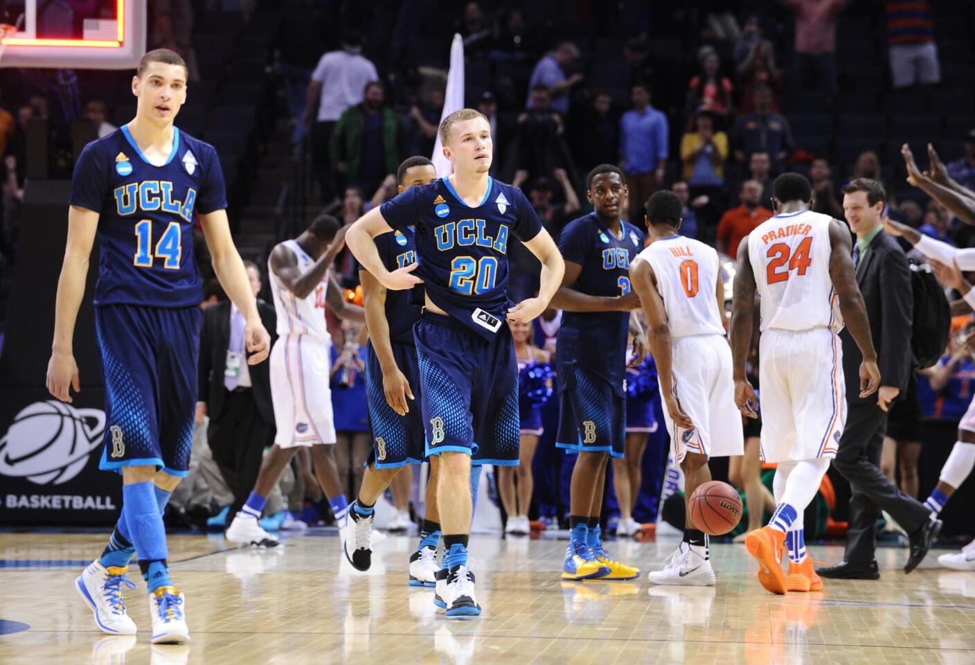 UCLA guards Zach LaVine (14), Bryce Alford (20) and Jordan Adams (3) leave the court as Florida players begin to celebrate after defeating the Bruins, 79-68, in the NCAA tournament South Regional semifinal on Thursday night in Memphis, Tenn.