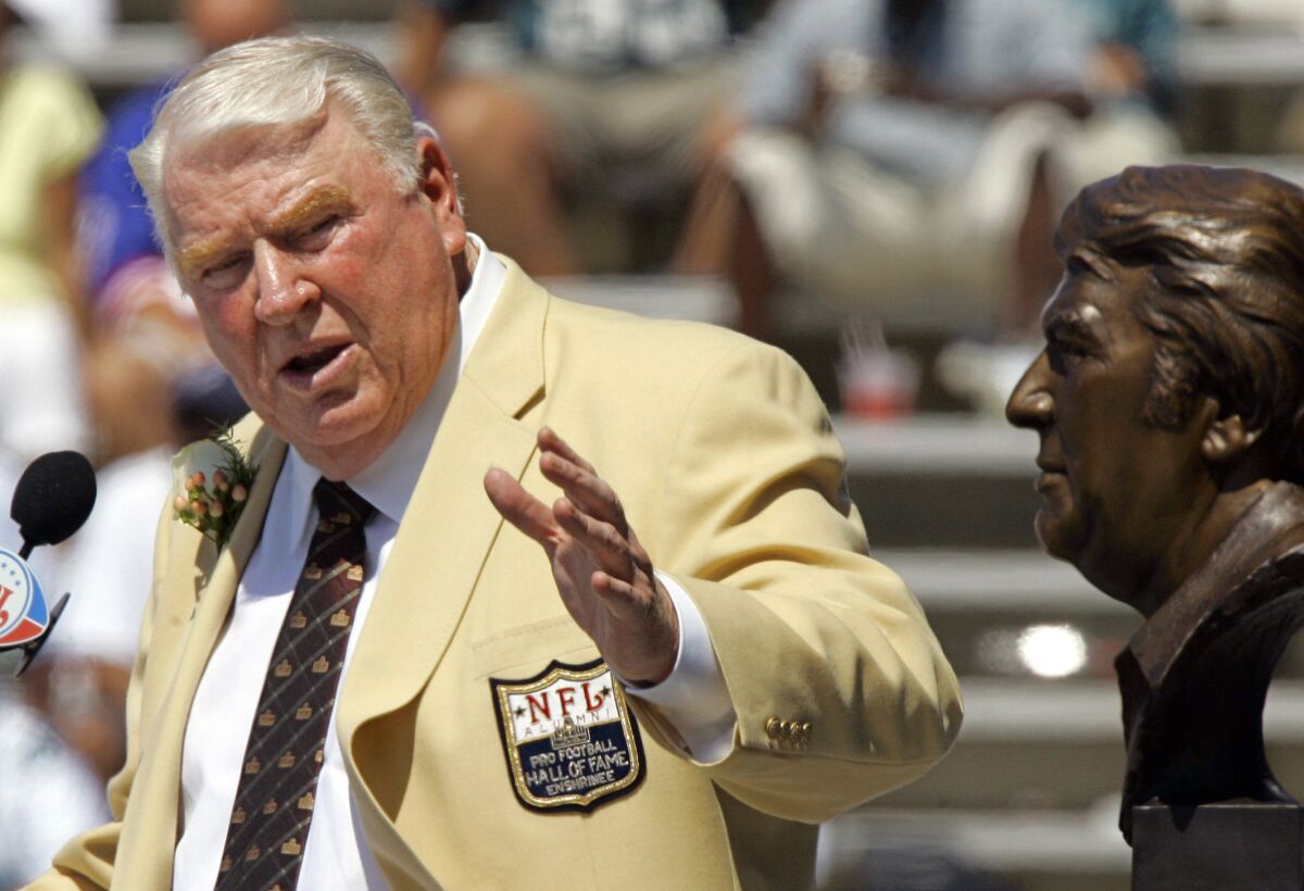 Former Raiders coach John Madden gestures toward a bust of himself during his Pro Football Hall of Fame enshrinement.