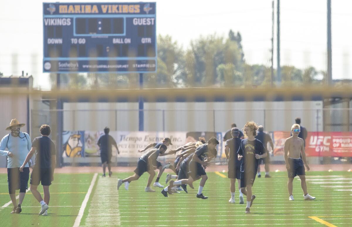 Marina High School football players go through agility drills on campus Tuesday in Huntington Beach.
