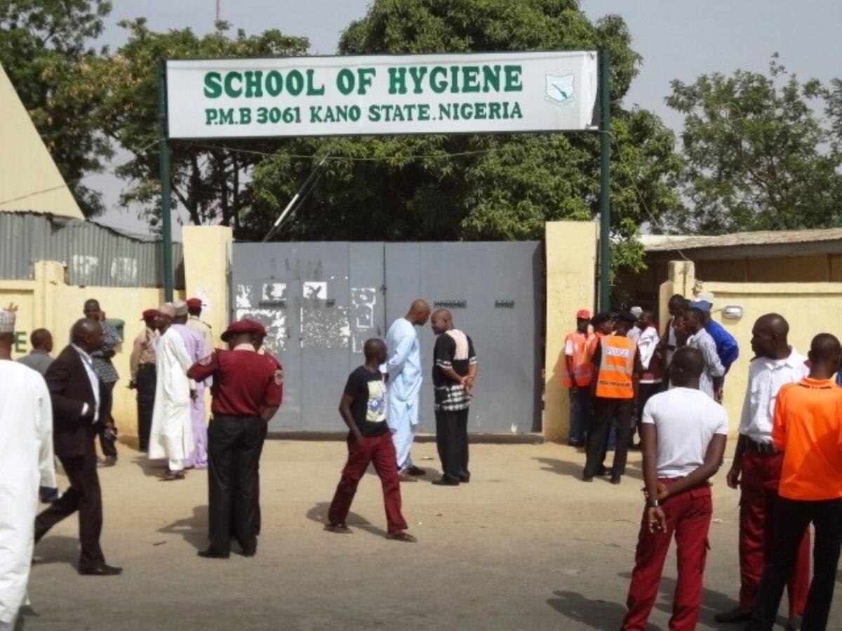 Policemen and others stand in front of the public health college in the northern Nigerian city of Kano where a bomb blast on Monday killed at least eight people.
