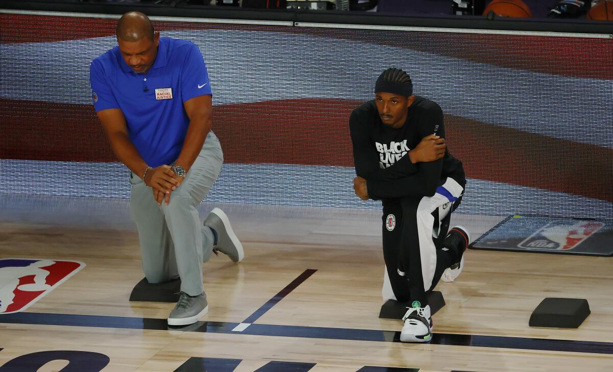 Clippers' Lou Williams, right, and coach Doc Rivers take a knee during the national anthem.