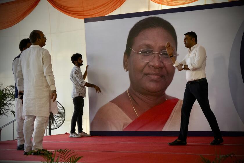 Workers put up a giant hoarding of Droupadi Murmu for her felicitation, before she was announced as the country's new President, in New Delhi, India, Thursday, July 21, 2022. Murmu, who hails from a minority ethnic community, was chosen Thursday as India’s new president, a largely ceremonial position. (AP Photo/Manish Swarup)