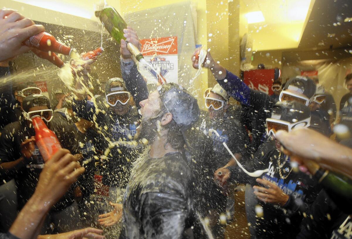 Pitcher Clayton Kershaw, center, celebrates with teammates in the locker room after the Dodgers beat the Giants to clinch the NL West title on Tuesday.