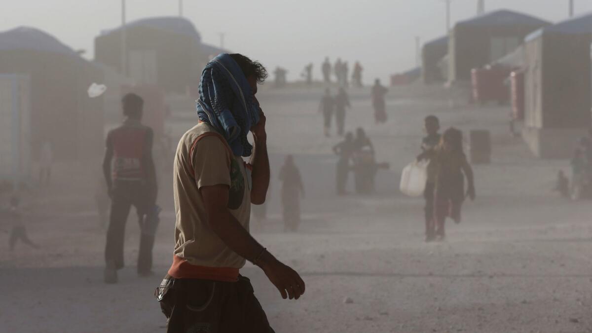 Syrian displaced people, who fled the battle between the U.S.-backed Syrian Democratic Forces and Islamic State militants in Raqqa city, walk in the dust at a refugee camp in northeast Syria on July 19.