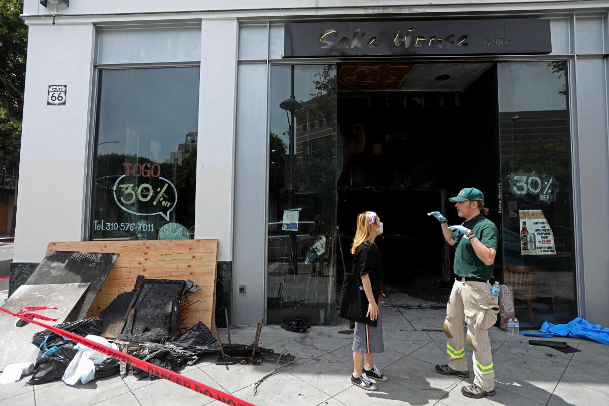 People stand outside a burned-out restaurant building with debris outside