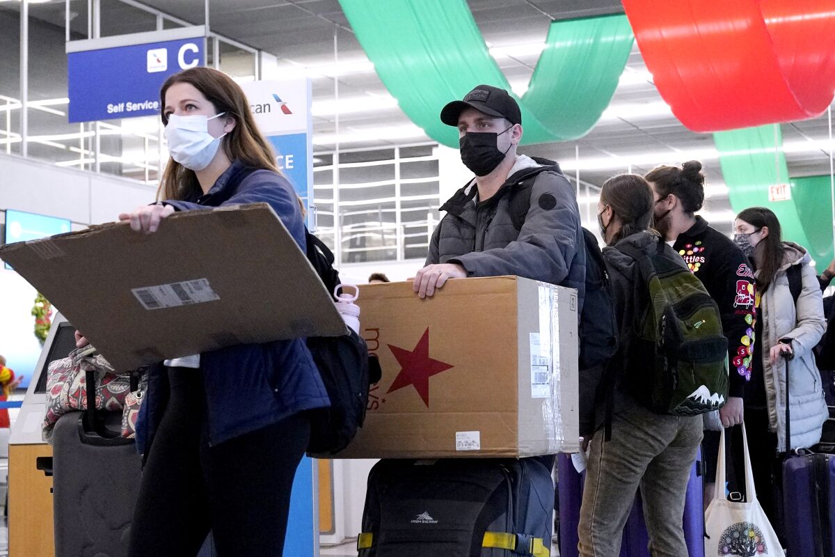FILE - Travelers line up wearing protective masks indoors at O'Hare International Airport in Chicago, Dec. 28, 2021. U.S. District Judge Kathryn Kimball Mizelle in Tampa, Fla., on April 18, 2022, voided the national travel mask mandate as exceeding the authority of U.S. health officials. The mask mandate that covers travel on airplanes and other public transportation was recently extended by President Joe Biden's administration until May 3. (AP Photo/Nam Y. Huh, File)