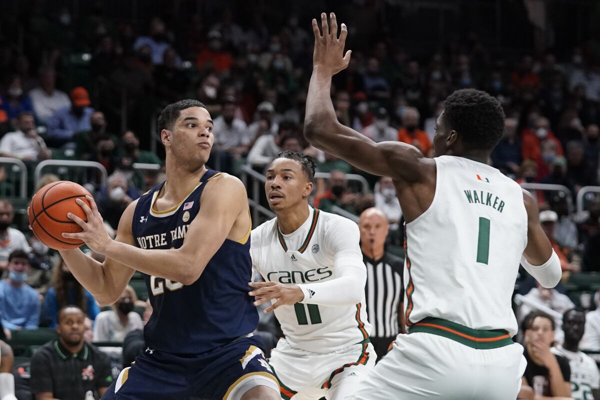 Notre Dame forward Paul Atkinson Jr., left, looks for an opening past Miami guard Jordan Miller (11) and forward Anthony Walker (1) during the first half of an NCAA college basketball game, Wednesday, Feb. 2, 2022, in Coral Gables, Fla. (AP Photo/Wilfredo Lee)