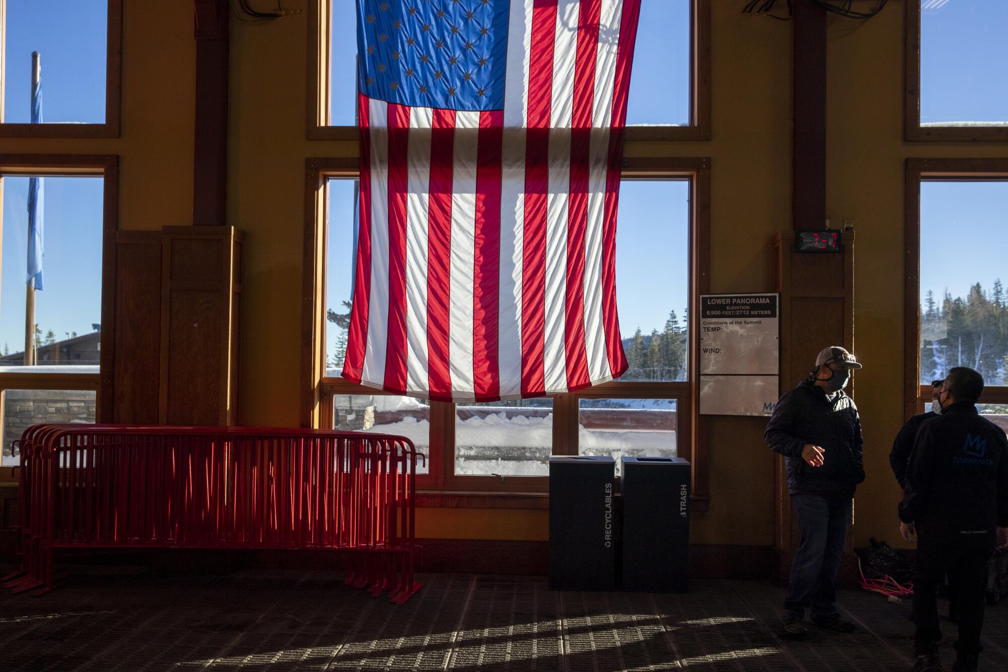 With an enormous American flag as a backdrop, ski area custodial employees confer at the Panorama Gondola base station.