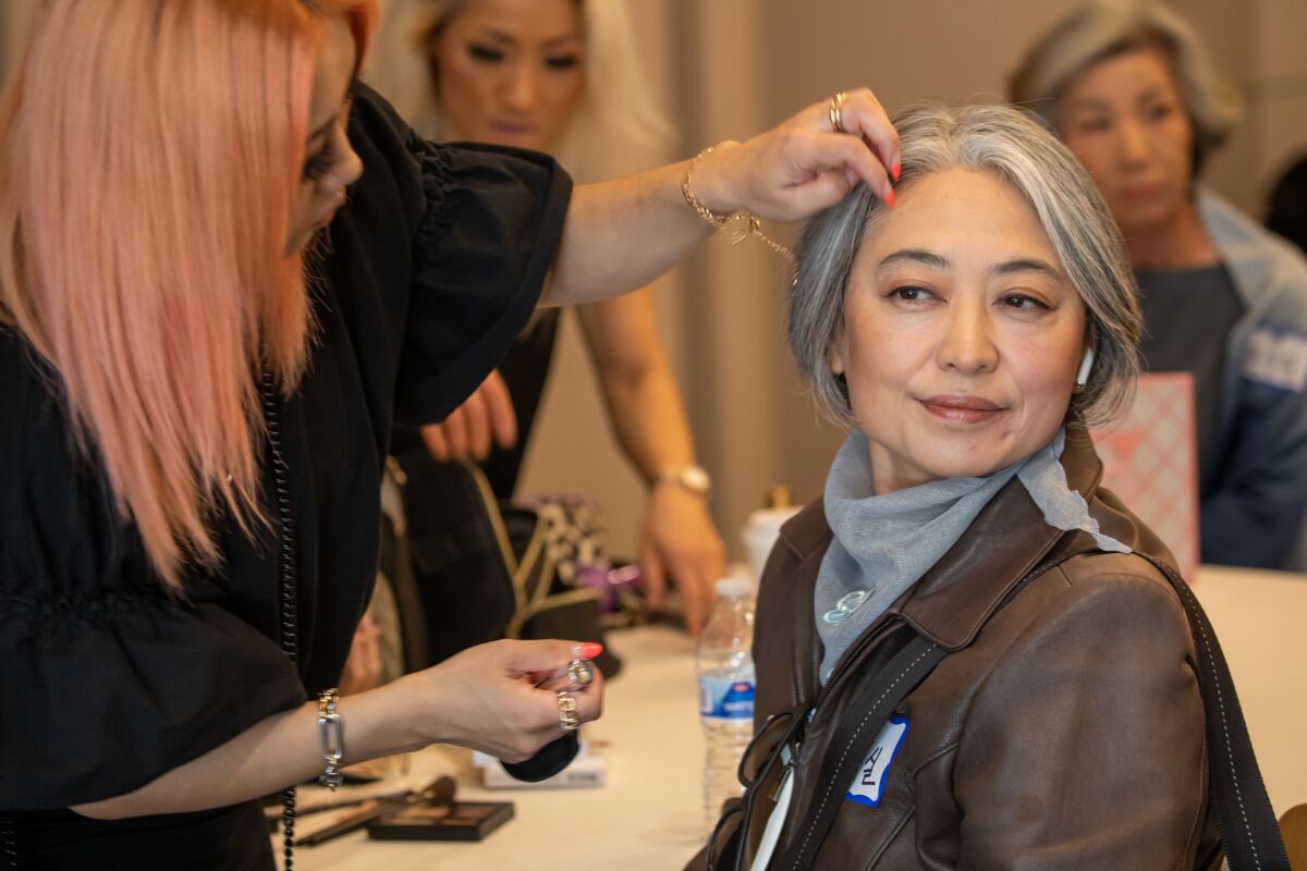 Makeup artist Junyoung McArdle, left, helps Grace Ju, 55, get ready for her Silver Models USA senior modeling audition.