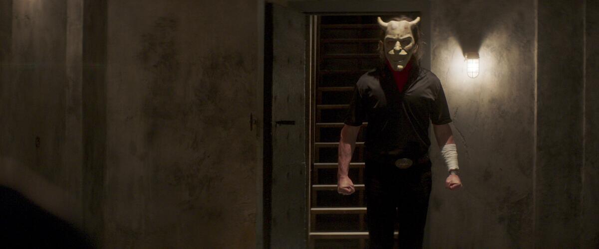 A man in a horned mask walks while clenching his fists 
