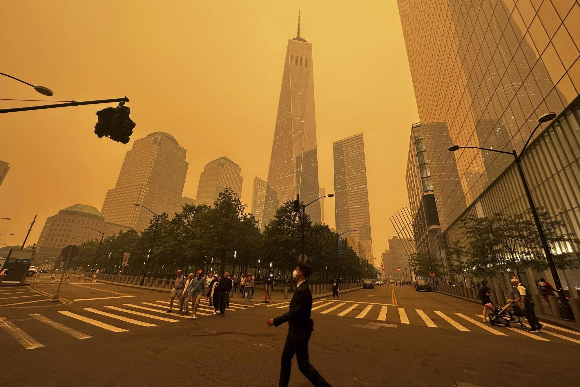 Pedestrians walk along streets while smoke fills the sky around several skyscrapers