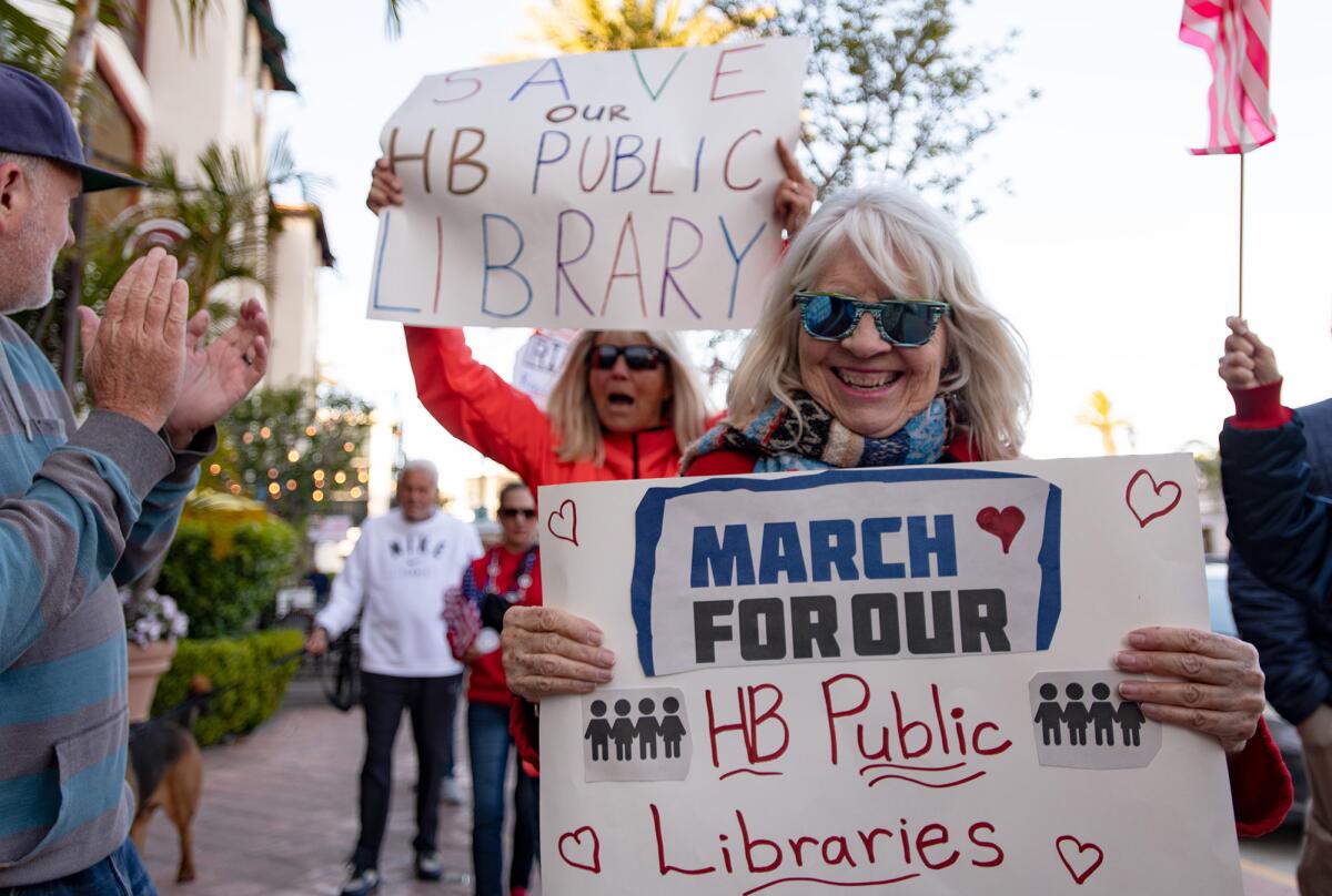 Demonstrators wave signs and shout slogans while marching in protest in Huntington Beach on Friday.