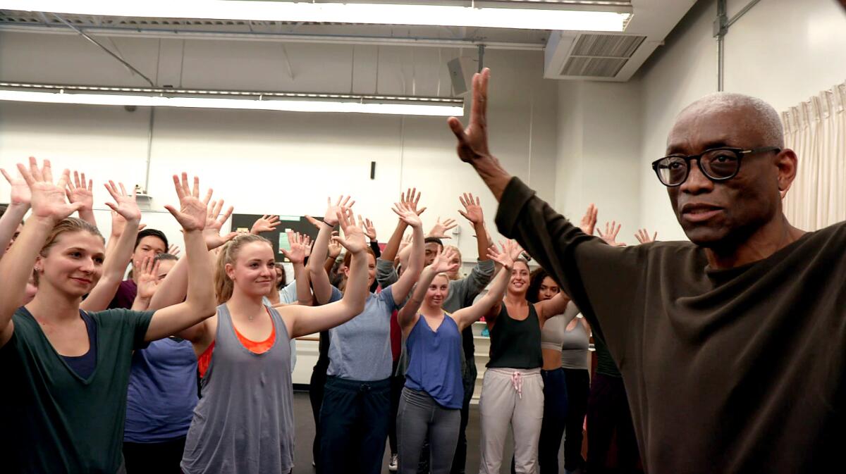 Bill T. Jones in rehearsal with students with arms raised.