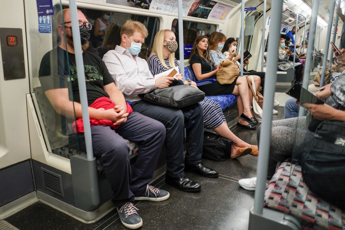 FILE - In this file photo dated Monday, July 19, 2021, people sit on an Underground train in London, as face masks and social distancing rules are relaxed along with limits on the number of people attending theater performances or big events. As Britain enjoys a summertime lull in COVID-19 cases, August 2021, the nation’s attention has turned to the end of pandemic-related restrictions and holidays in the sun, but scientists are warning the public not to be complacent about the delta variant. (AP Photo/Alberto Pezzali, FILE)