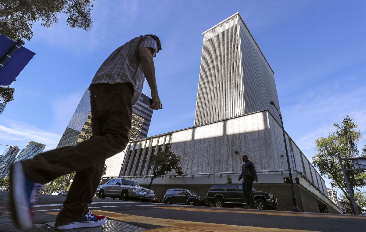 Pedestrians cross A Street with the former Sempra building, located on Ash Street