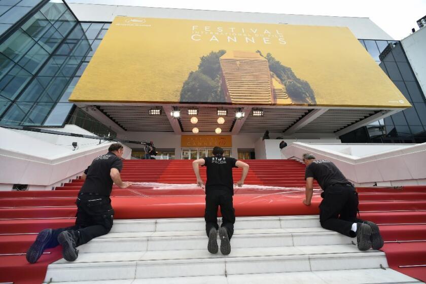 Staff members lay out the red carpet outside the Palais des Festivals in the southeastern French city of Cannes on May 10, the eve of the opening ceremony of the 69th Cannes Film Festival.