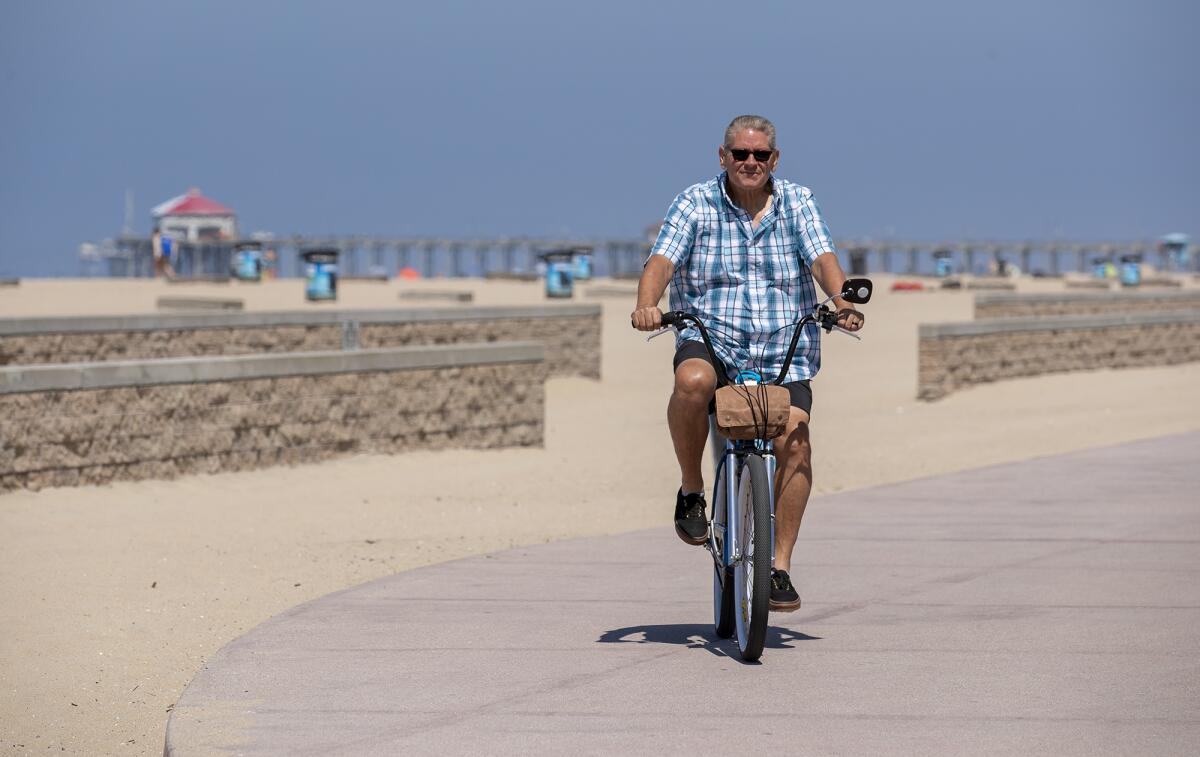 Chris Hill, who underwent gastric sleeve surgery in 2021, rides his bike along the path in Huntington Beach on June 27.