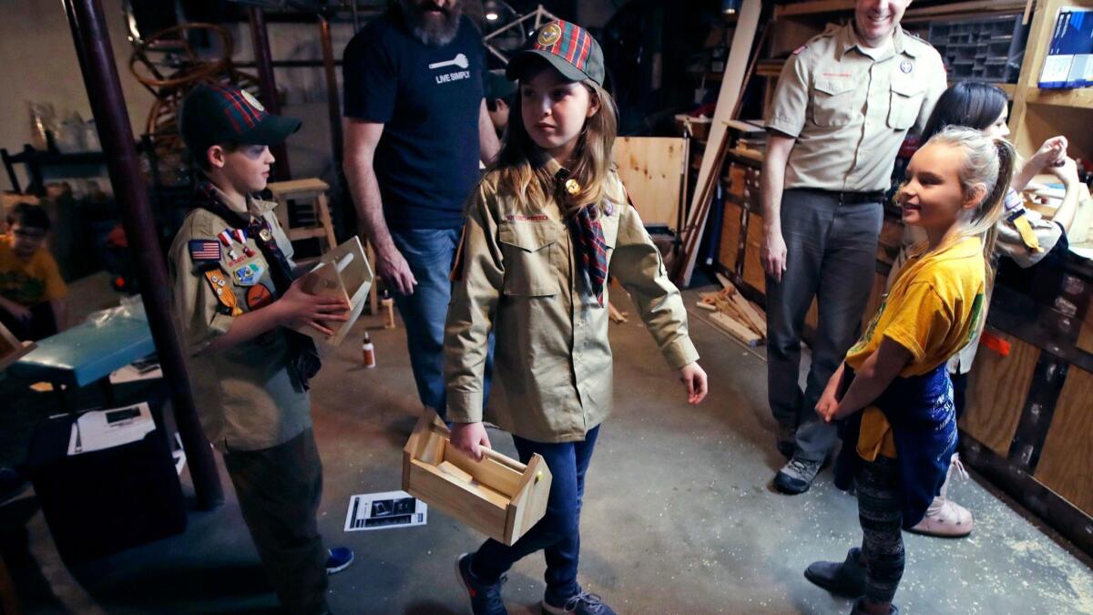 Tatum Weir, center, carries a tool box she built at a Cub Scout meeting in Madbury, N.H. Fifteen communities in New Hampshire are part of an "early adopter" program to allow girls to become Cub Scouts and eventually Boy Scouts.