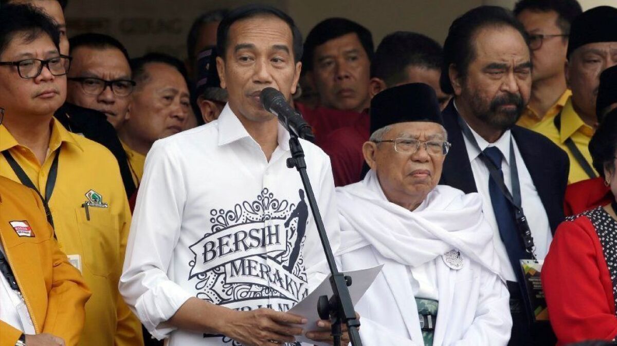 Indonesian President Joko Widodo, center left, speaks alongside his running mate, Ma'ruf Amin, center right, prior to registering as candidates for the 2019 election.