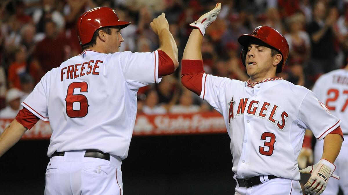Angels teammates David Freese, left, and J.B. Shuck celebrate after scoring runs during the fifth inning of the Angels' 6-4 win over the Cleveland Indians at Angel Stadium on Tuesday night.