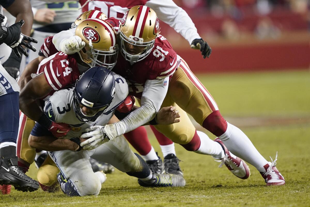 Seattle Seahawks quarterback Russell Wilson, bottom, is tackled under San Francisco 49ers defensive back K'Waun Williams (24) and defensive end Arik Armstead (91) during a game in Santa Clara on Nov. 11.