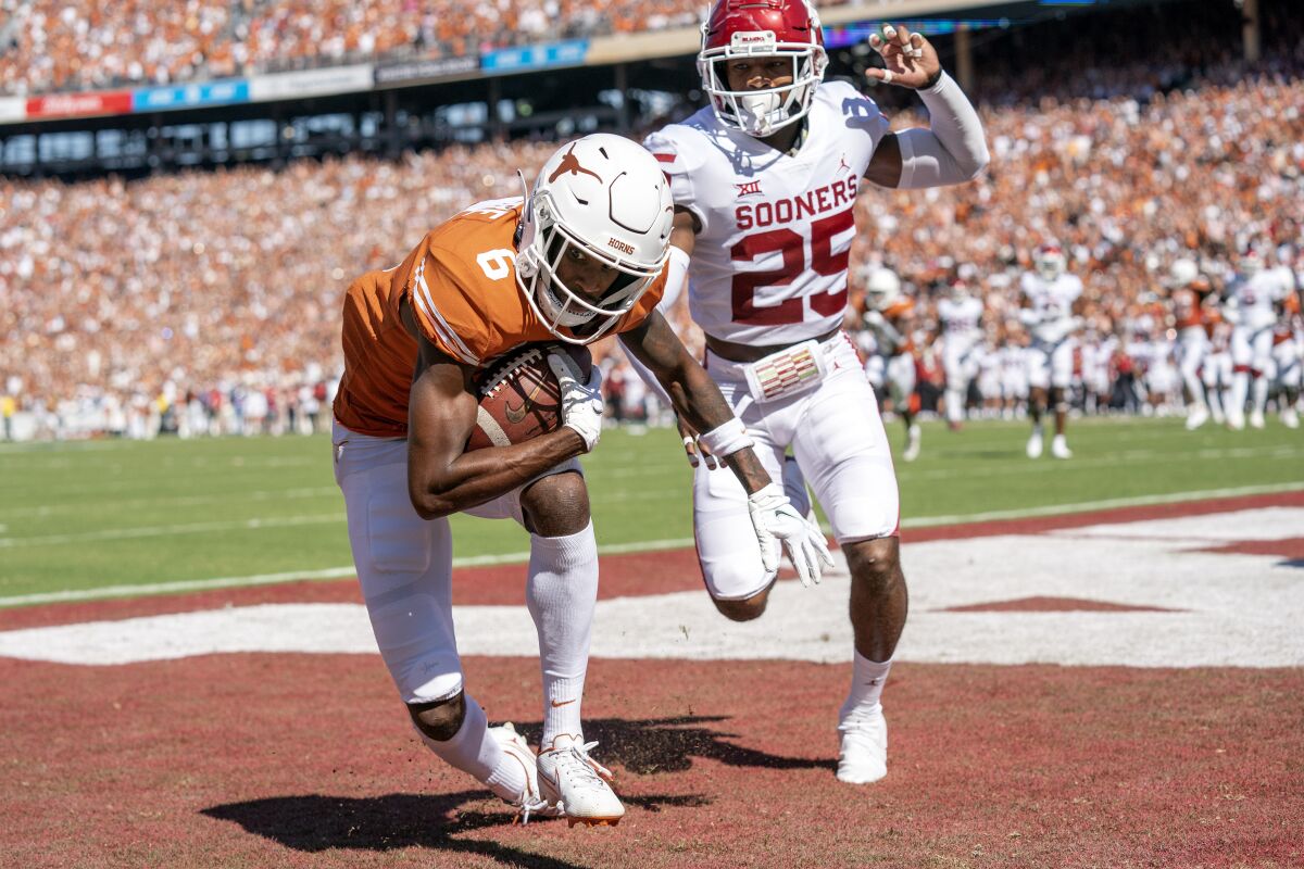 Texas wide receiver Joshua Moore (6) comes down with a touchdown reception in front of Oklahoma defensive back Justin Broiles (25) during the first half of an NCAA college football game at the Cotton Bowl, Saturday, Oct. 9, 2021, in Dallas. (AP Photo/Jeffrey McWhorter)