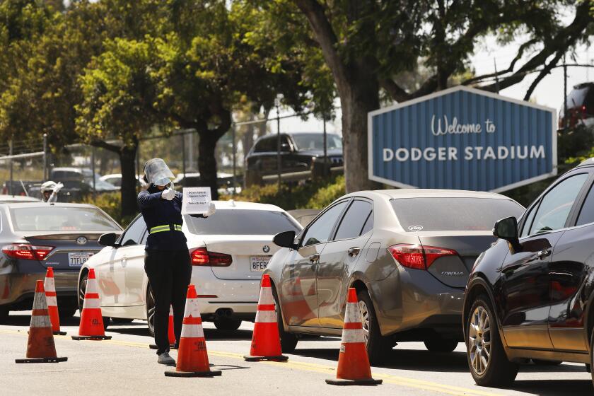 LOS ANGELES, CA - JULY 07: People confirm that drivers have a appointment for Coronavirus Covid-19 testing which has resumed at Dodger Stadium with a new drive-through testing site on Tuesday. Dodger Stadium on Tuesday, July 7, 2020 in Los Angeles, CA. (Al Seib / Los Angeles Times)
