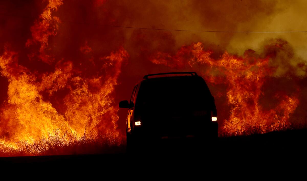 A motorist drives past flames from the Fairview fire.