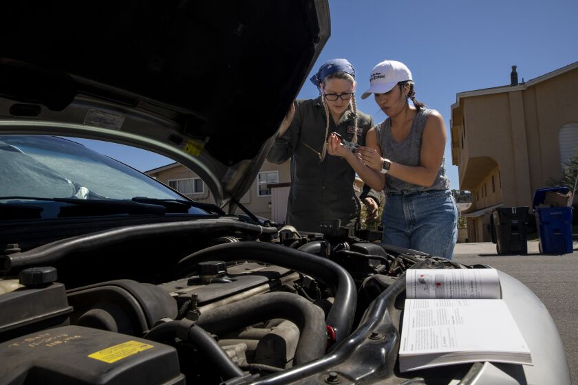 San Diego, CA - September 21: Talena Handley, 34, left, teaches Natallie Rocha, small business reporter for The San Diego Union-Tribune, how to check a fuse on Wednesday, Sept. 21, 2022 in San Diego, CA. They look at Rocha's 2007 Volvo. Handley started her own business called Girlie Garage where she educates people, usually by phone, Zoom or FaceTime, on how to fix their car. She has been a mechanic for about 15 years. (Ana Ramirez / The San Diego Union-Tribune)