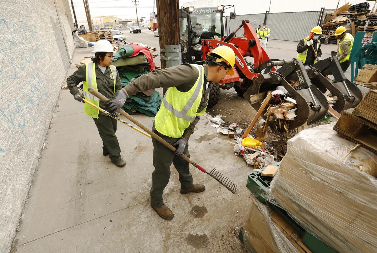 City of Los Angeles Bureau of Sanitation crews clean up items dumped on the street near the homeless encampment of Rickey Harris at 41st Place and Alameda St. (Al Seib / Los Angeles Times)