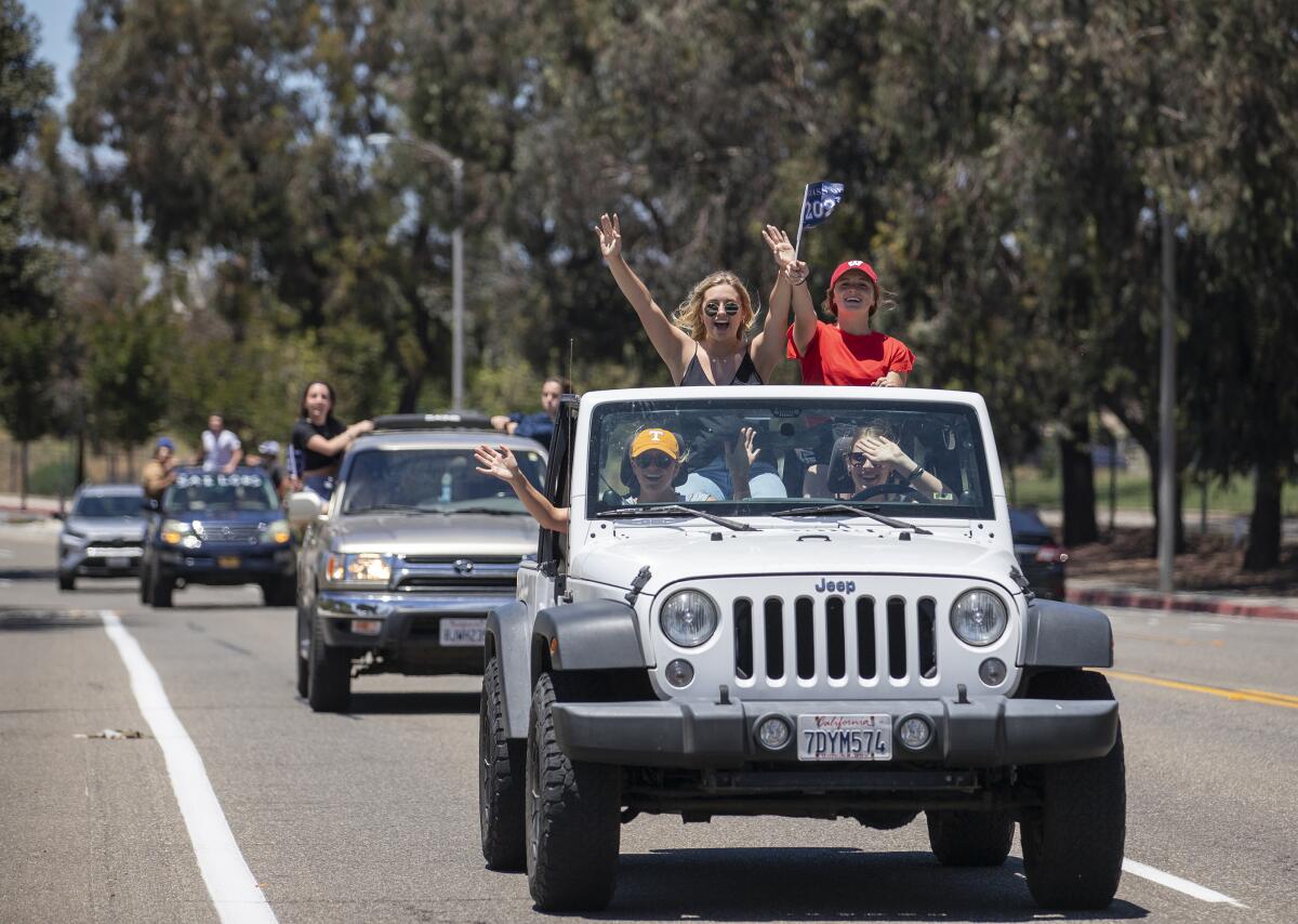 Students drive by Estancia High School during a senior graduation parade.
