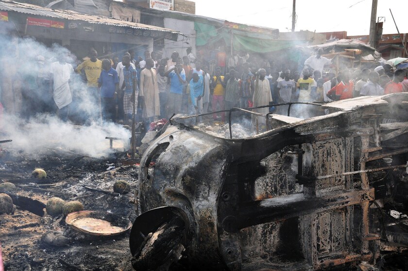People gather at the scene of a car bombing that rocked a crowded Market in the Nigerian city of Maiduguri.
