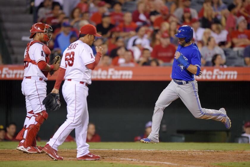 Toronto's Jose Bautista, right, scores past Angels catcher Carlos Perez, left, and relief pitcher Fernando Salas during the eighth inning on Saturday night.