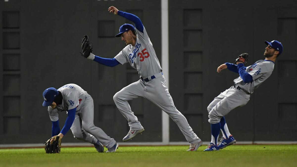 Dodger Cody Bellinger makes a leaping catch between teammates Enrique Hernandez, left, and Chris Taylor.