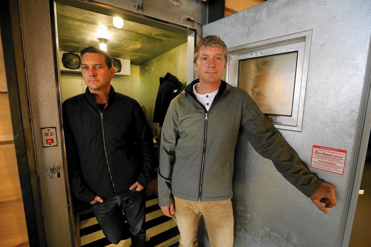 Aether's Jonah Smtih, left, and Palmer West pause at the door of the coat-test freezer at the Los Angeles store.