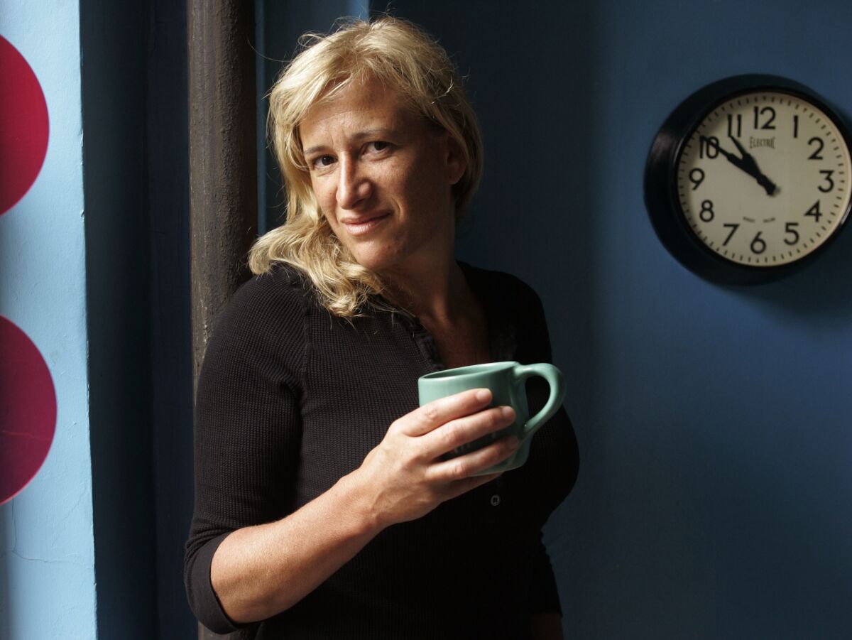 Author Melissa Bank poses for a portrait with a coffee mug in hand.