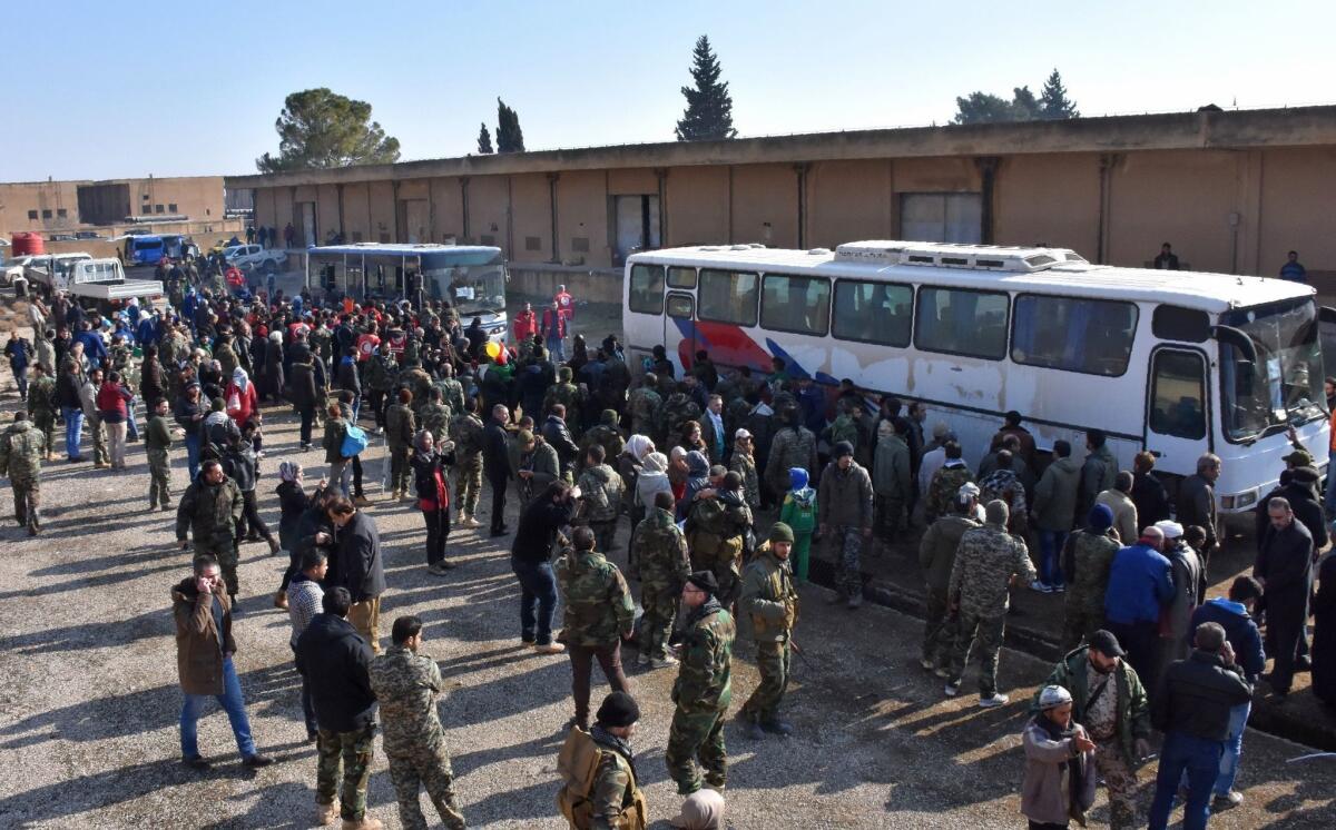 Syrians evacuated from the villages of Foua and Kfarya are welcomed by pro-government forces as they arrive in Jibreen on the eastern outskirts of Aleppo on Monday.